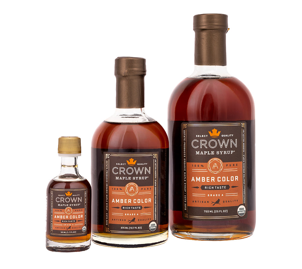 Bio-Ahornsirup von Crown Maple: Amber Color Rich Taste, Grade A, in drei Glasflaschen-Größen vor weißem Hintergrund.